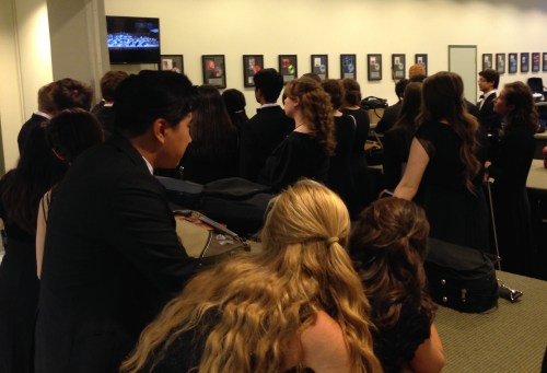 a rapt audience of Curb Youth Symphony musicians watch Jocelyn Hartley's performance on the monitor in the musician's lounge shortly before they join her on stage